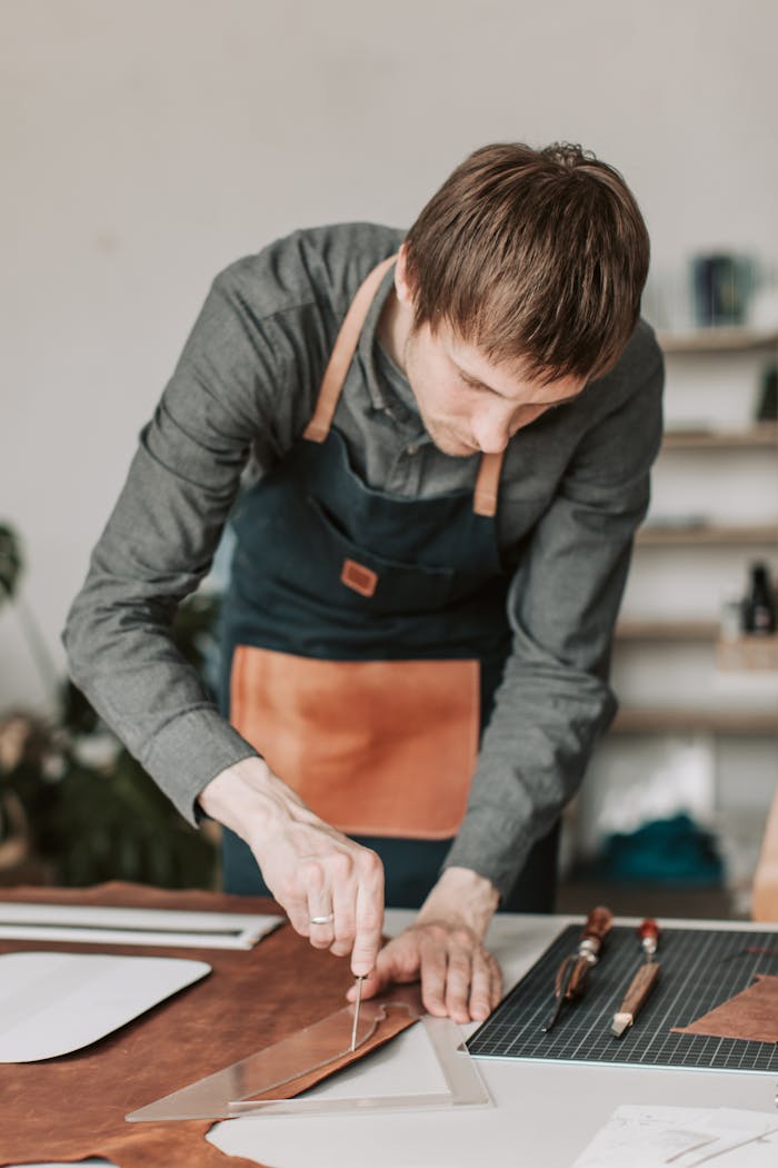 A leathersmith focuses intently on crafting leather goods in a workshop environment.