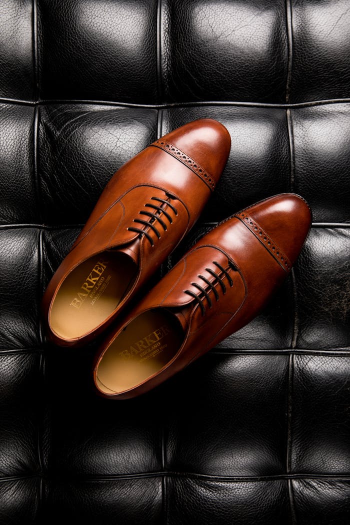 Top view of classic brown leather Oxford shoes on a contrasting black leather surface, showcasing luxury footwear design.